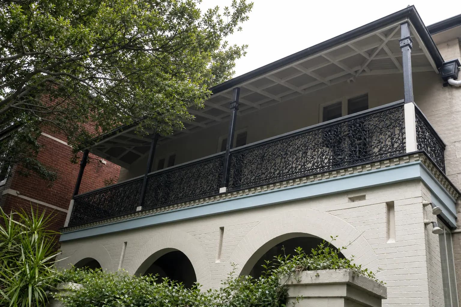 Restored heritage verandah with timber posts, balustrade, and iron lacework on a Sydney facade