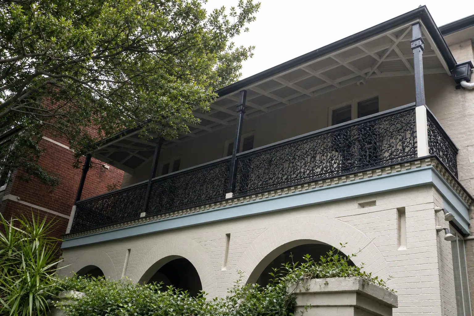 Federation-era building with ornate iron balcony and arched brick colonnade