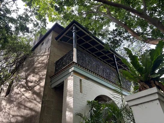 Heritage building with wrought-iron balcony and sandstone walls